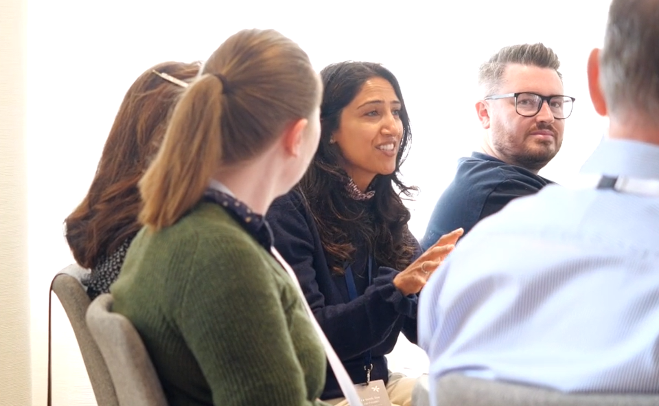 A group of dental professionals seated in discussion during the Envisage Clinical Circle event, with one woman speaking while others listen attentively.